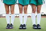 Legs, feet and a woman hockey team outdoor on a field for a game or competition together in summer. Fitness, exercise or sports with people on a pitch of a grass for training or teamwork on match day