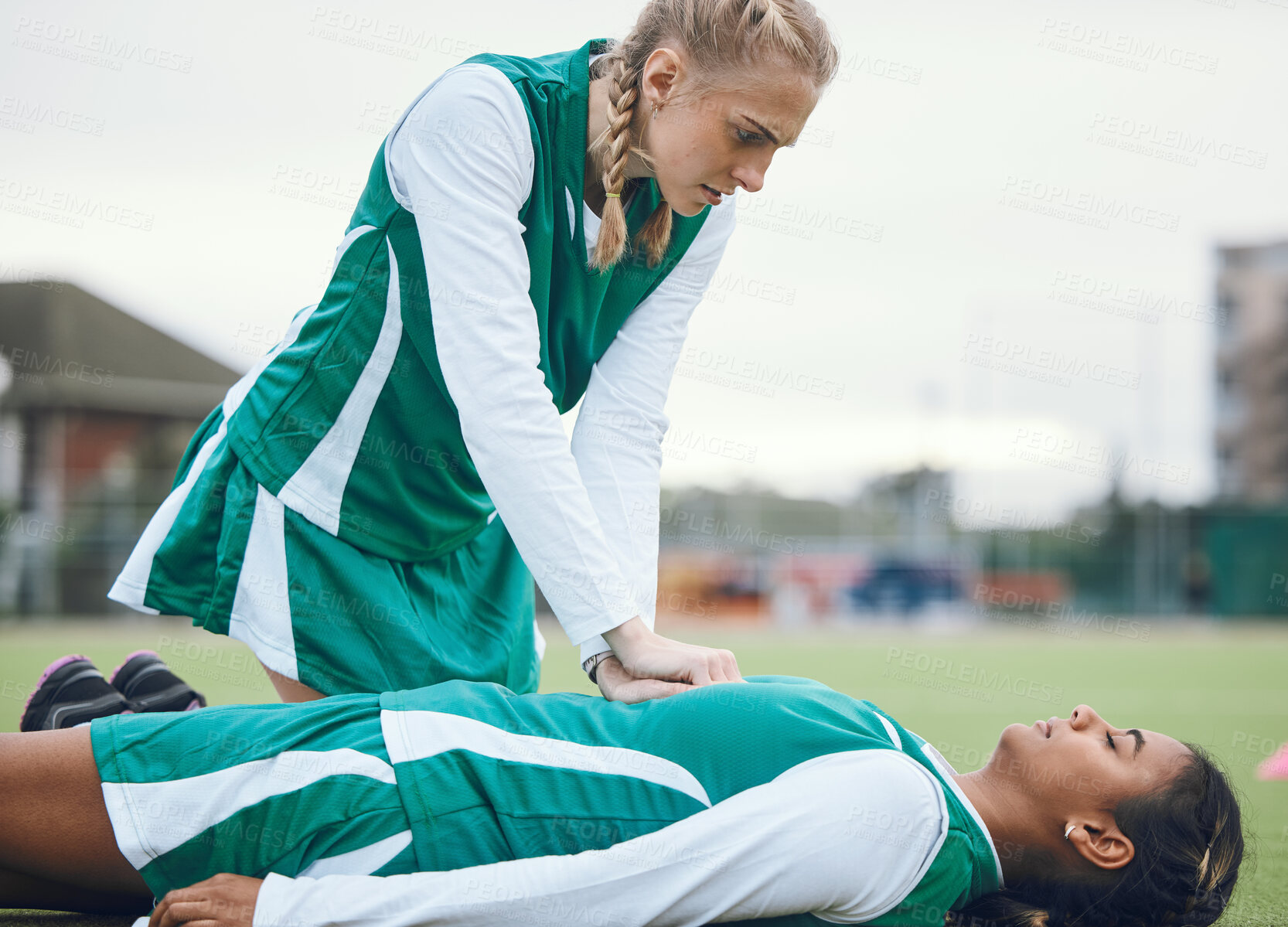 Buy stock photo First aid, cpr and accident with a hockey player on a field to save a player on her team during an emergency. Fitness, sports and heart attack with a woman helping her friend on a field of grass