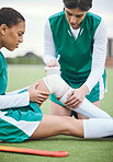 Sports, knee pain or woman with a bandage on field or turf struggling with first aid in game or match. Emergency, bad injury or hockey athlete on artificial grass with medical help from an accident