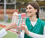 Cheers, water bottle and woman with hockey team on break together at sports training, match or competition. Smile, celebrate and people on a field for fitness or exercise in victory with teamwork