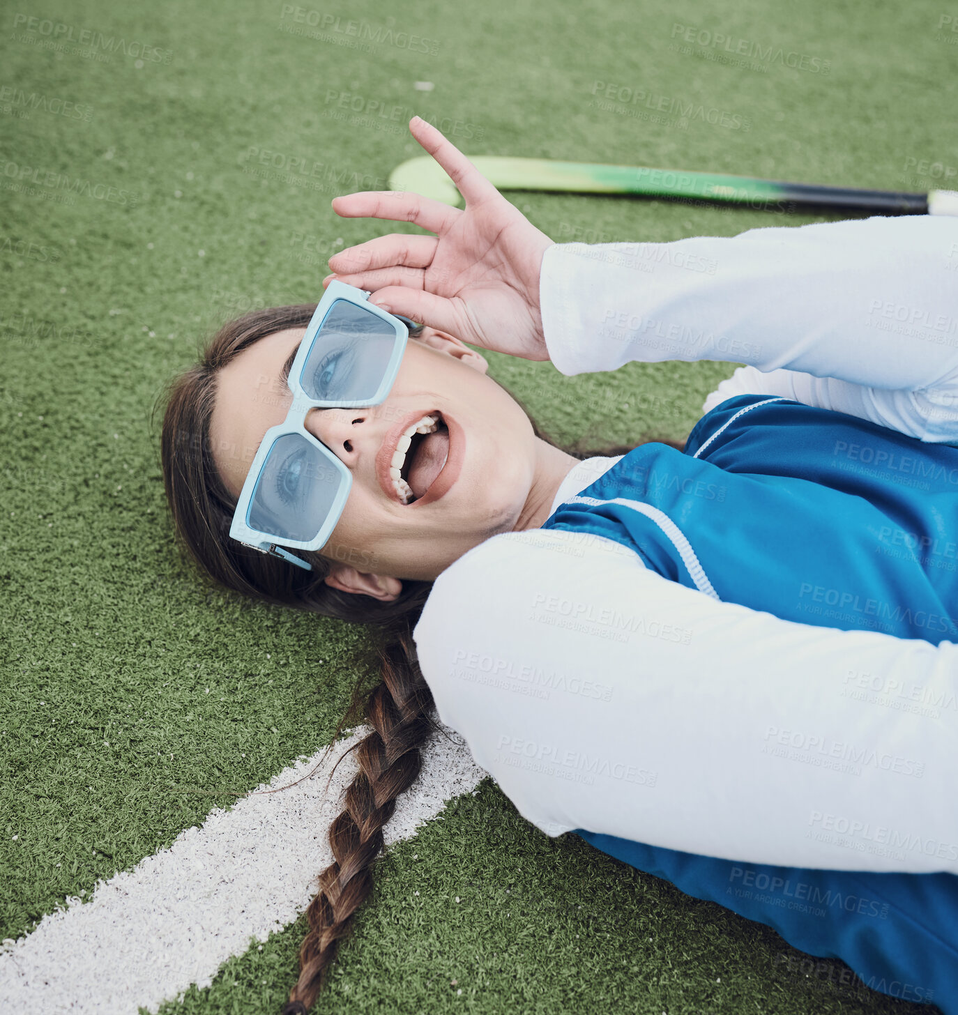 Buy stock photo Woman, hockey and laying on field, break and closeup of sunglasses, pose and relax for practice, training and workout. Happy athlete, playful and excited for exercise, fashion and accessories for fun