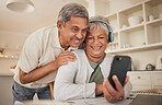 Phone, hug and senior couple with video call in a kitchen happy, headphones and communication. Love, smile and old people with smartphone app for virtual, conversation or contact chat in their house