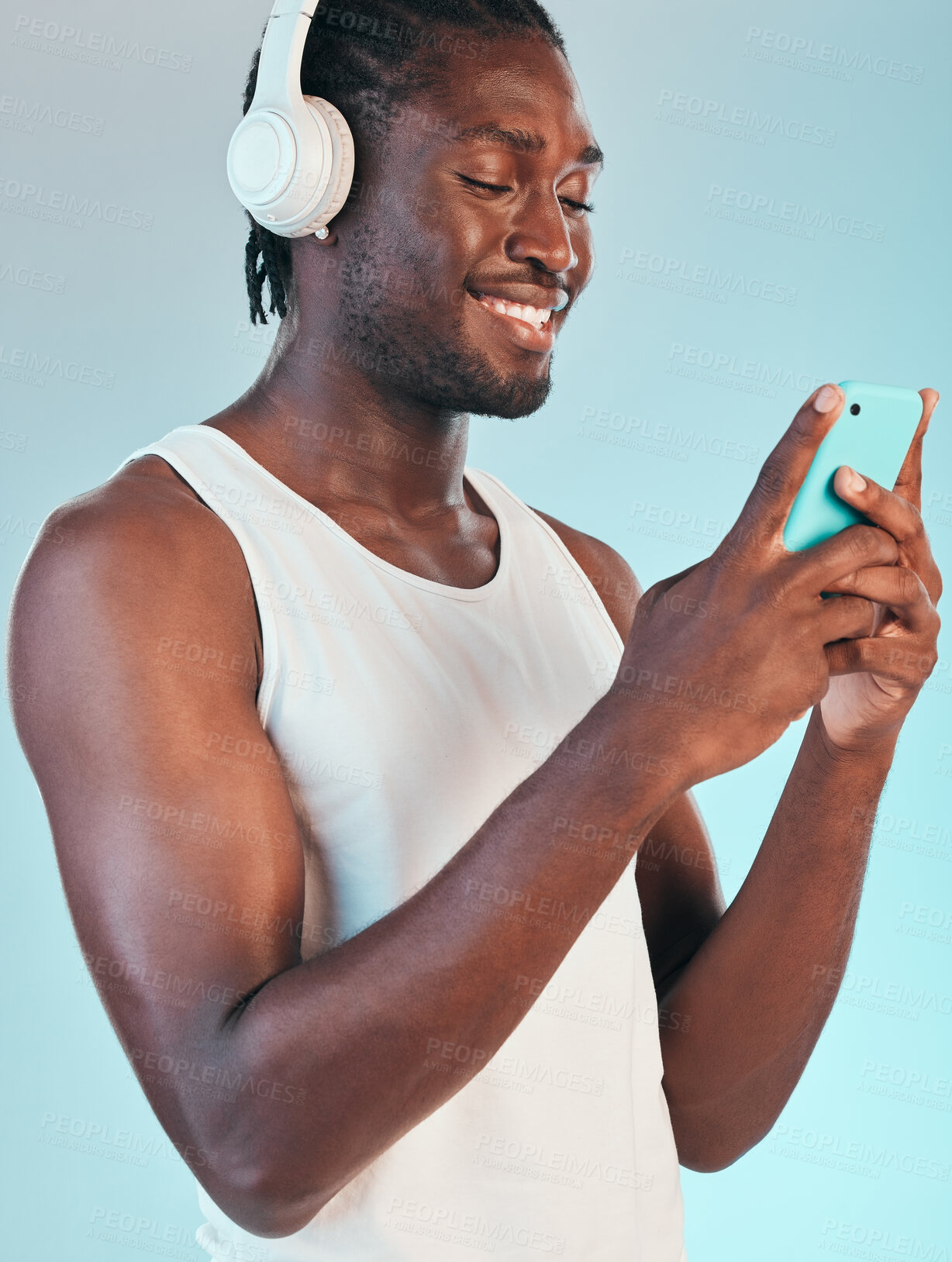 Buy stock photo Smartphone, headphones and black man listening to music, smile with audio streaming and chat isolated on blue background. Happiness, sound and mobile app, podcast or radio with connectivity in studio