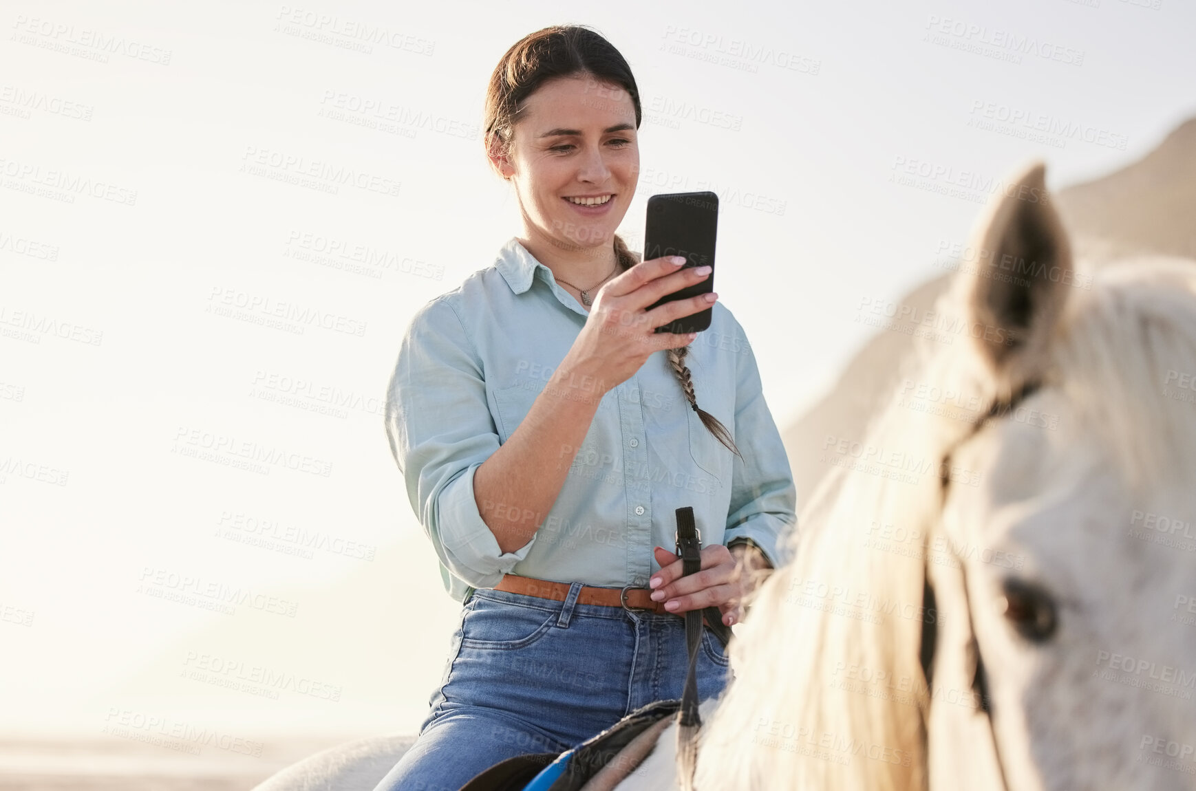 Buy stock photo Horse riding, phone and woman on beach with pet for travel using social media, website and web for chatting. Texting, smile and happy person or rider with animal on vacation or holiday at sunrise 