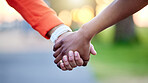 Interracial couple, holding hands and love in nature for support, trust or unity together. Closeup of people touching in romance, care or friendship walk in an outdoor park for partnership or duo