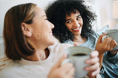 Buy stock photo Coffee, happy and lesbian couple on bed in conversation for bonding and relaxing together. Smile, rest and interracial lgbtq women laughing, talking and drinking latte in bedroom of modern apartment.