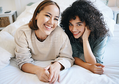 Buy stock photo Love, smile and portrait of lesbian couple on bed for bonding, resting and relaxing together. Happy, romance and young interracial lgbtq women laying in the bedroom of modern apartment or home.