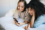 Phone, relax and young lesbian couple on a bed networking on social media, mobile app or the internet. Happy, technology and interracial lgbtq women scroll on cellphone in bedroom at modern apartment