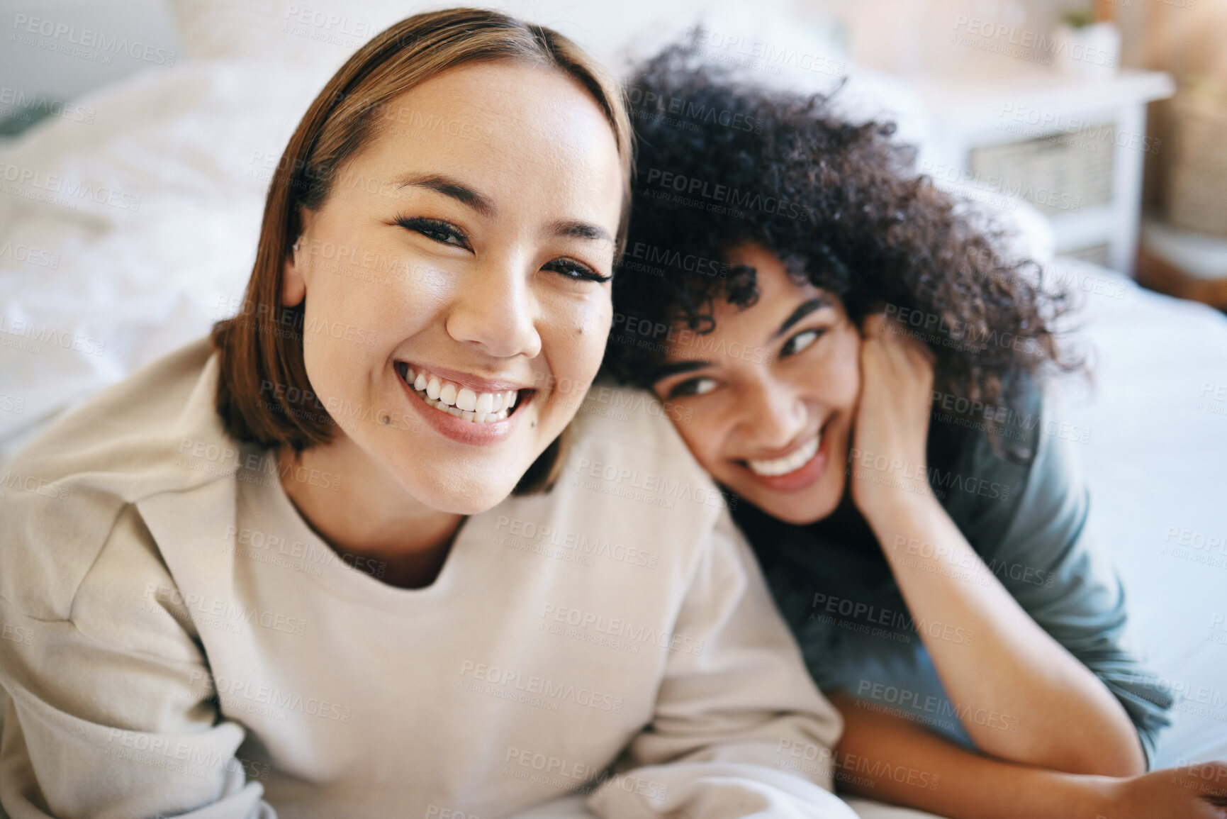 Buy stock photo Love, happy and portrait of lesbian couple relaxing on bed for bonding together on a weekend. Smile, romance and young interracial lgbtq women resting in the bedroom of modern apartment or home.