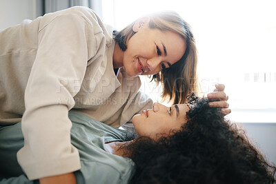 Buy stock photo Love, happy and lesbian couple with intimate moment on bed for bonding or relaxing together. Smile, romance and young interracial lgbtq women with affection in the bedroom of modern apartment or home