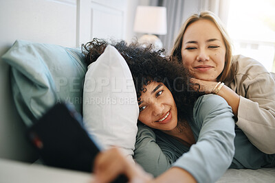 Buy stock photo Cellphone, relax and young lesbian couple on a bed networking on social media, mobile app or the internet. Happy, technology and interracial lgbtq women scroll on cellphone in bedroom at apartment.