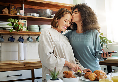 Buy stock photo Lesbian, couple and kiss in kitchen with breakfast in morning together with nutrition, love and support in home. Lgbt, women or cooking with healthy food and preparing vegan diet on counter in house