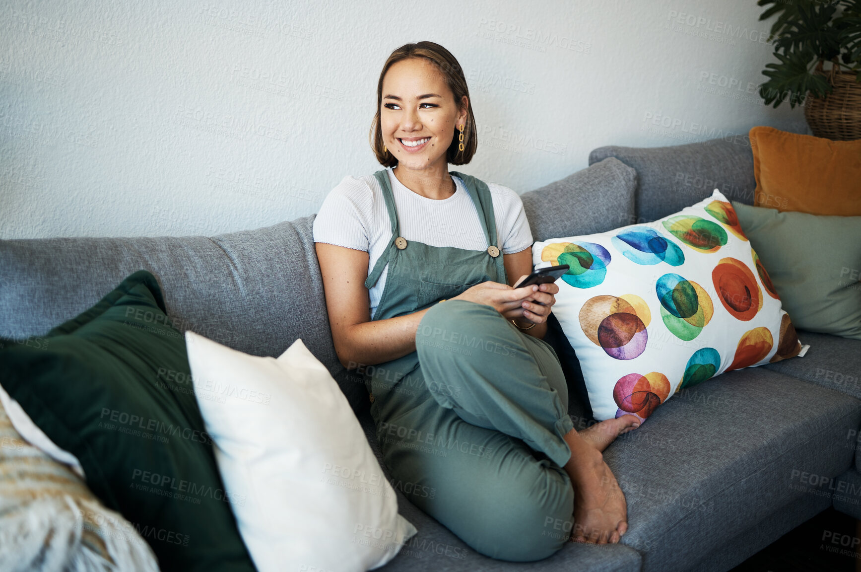 Buy stock photo Woman, phone and thinking on sofa of home for social media, internet post or conversation with smile. Person, smartphone and happiness for communication, networking and connectivity with technology