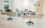 Empty office, interior and coworking space with laptop on desk in startup company. Computer, table and creative workplace room with wood furniture, chair and modern design in workspace for business