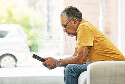 Buy stock photo Serious, mature man and reading bible in home, praying and thinking in living room on sofa. Person, holy book and gospel in house for learning religion, studying and Christian worship in retirement