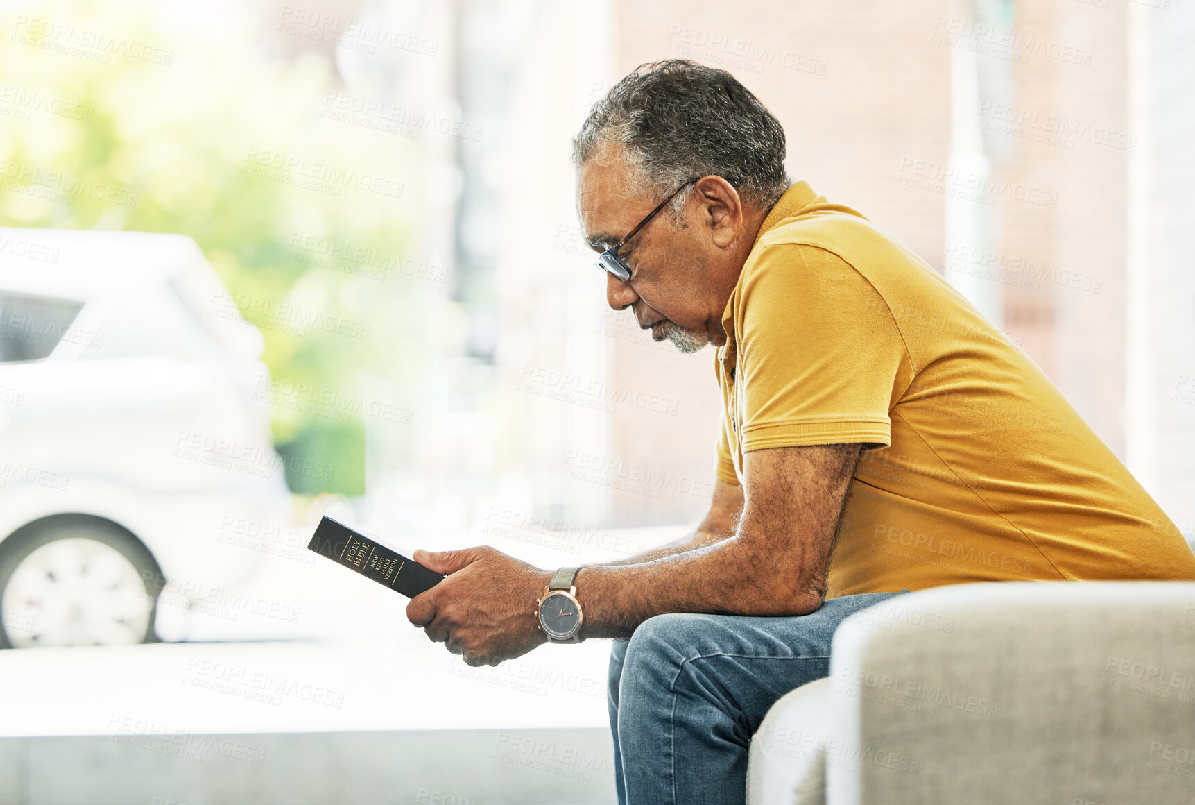 Buy stock photo Serious, mature man and reading bible in home, praying and thinking in living room on sofa. Person, holy book and gospel in house for learning religion, studying and Christian worship in retirement