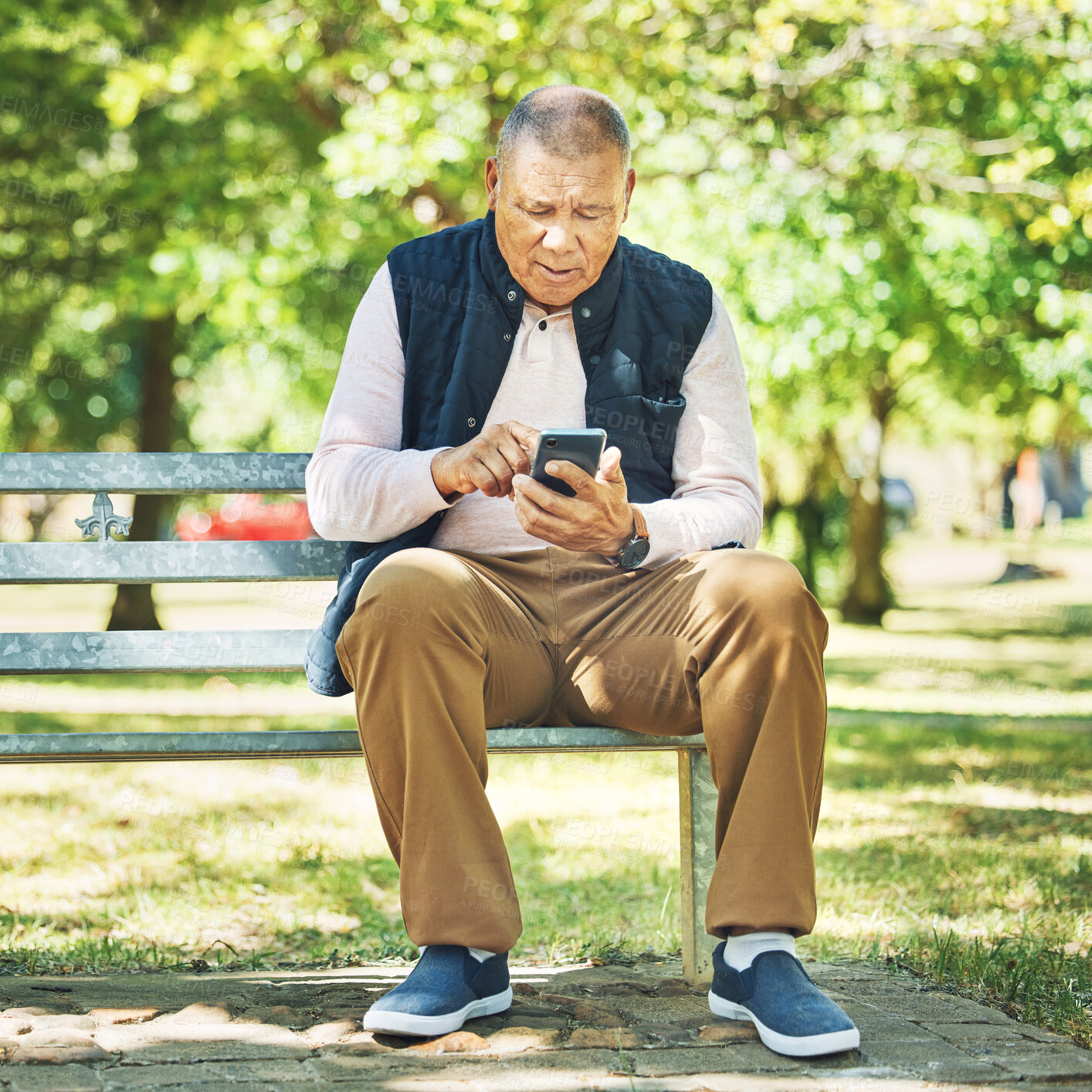 Buy stock photo Senior man, typing and phone on park bench, learning and network with technology online, nature and outdoor. Elderly person, message and email on smartphone, digital and contact in retirement