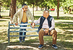 Senior friends, men and relax at park bench, talk and bonding outdoor with phone. Elderly people sitting together in garden, communication and serious conversation in nature for retirement in spring