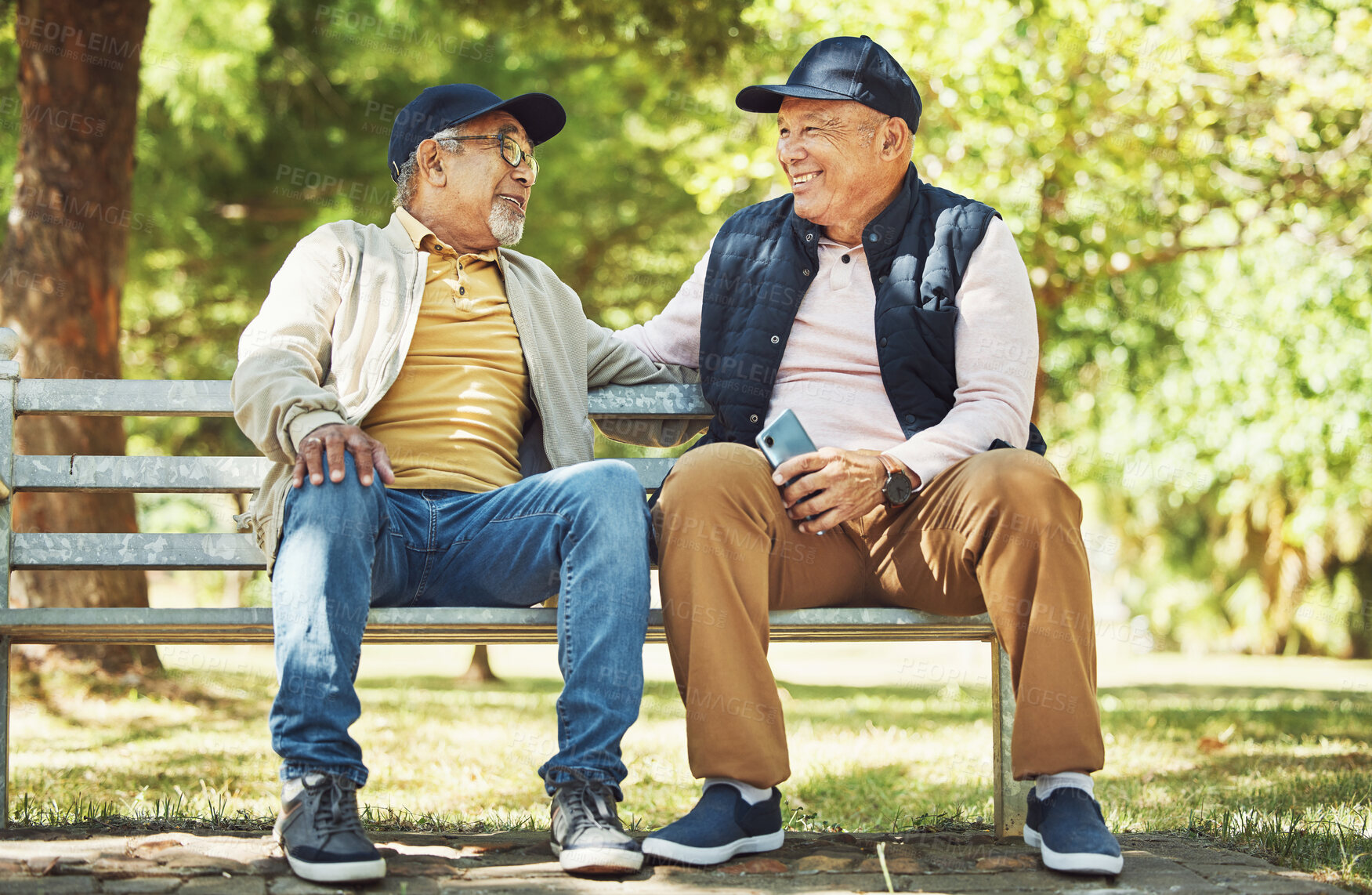 Buy stock photo Senior friends, smile and relax on park bench, talking and bonding outdoor in retirement. Happy elderly men sitting together in garden, communication and chat in nature in the morning with phone.