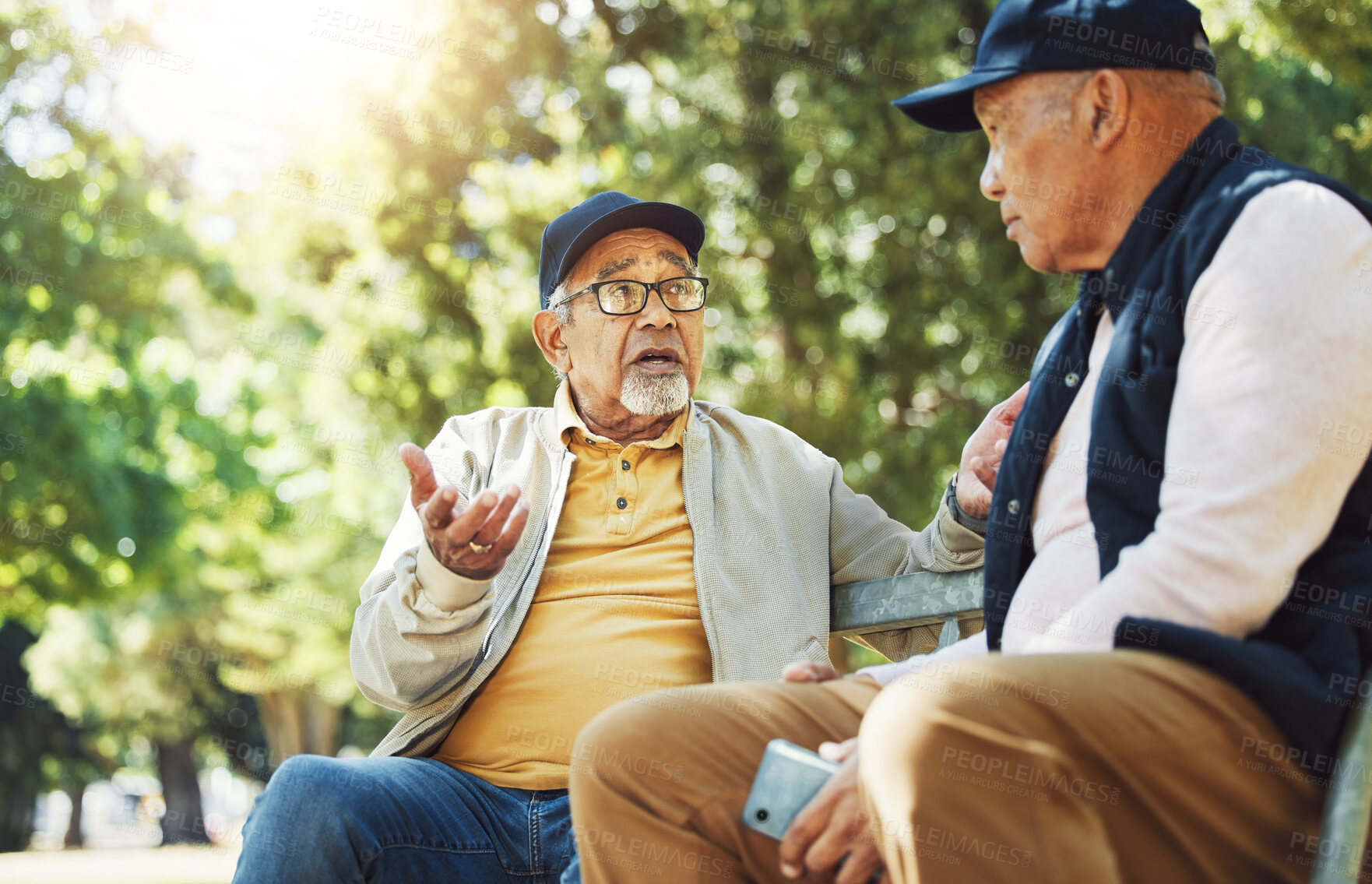 Buy stock photo Senior friends, men and conversation on park bench, bonding and relax outdoor with phone. Elderly people sitting together in garden, communication and serious in nature for retirement in the morning