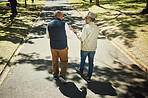 Senior, friends walking and talking in park, nature and outdoor in retirement with support and communication. Elderly, men and above people on sidewalk in New York with conversation and community