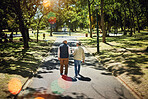 Men, friends walking and talking in park, nature and outdoor in retirement with support, communication or bokeh. Mature, people and sidewalk or path in New York with conversation and social community