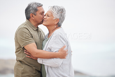 Buy stock photo Senior, couple and kiss on the beach for retirement vacation, holiday or adventure in summer with care. Elderly, man or woman for walking by ocean or sea with journey and happiness for relax and love