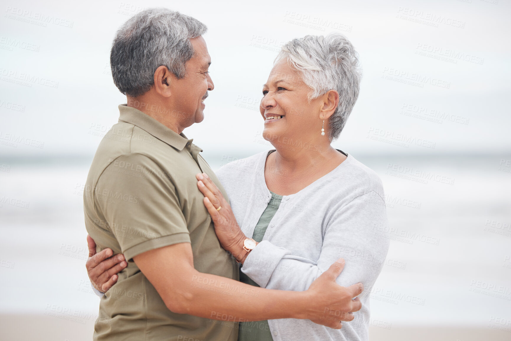 Buy stock photo Elderly, couple and hug with smile on beach in nature together for holiday, relax and connection outdoor. Commitment, man or woman with love embrace for peace, trust and vacation at ocean or sea