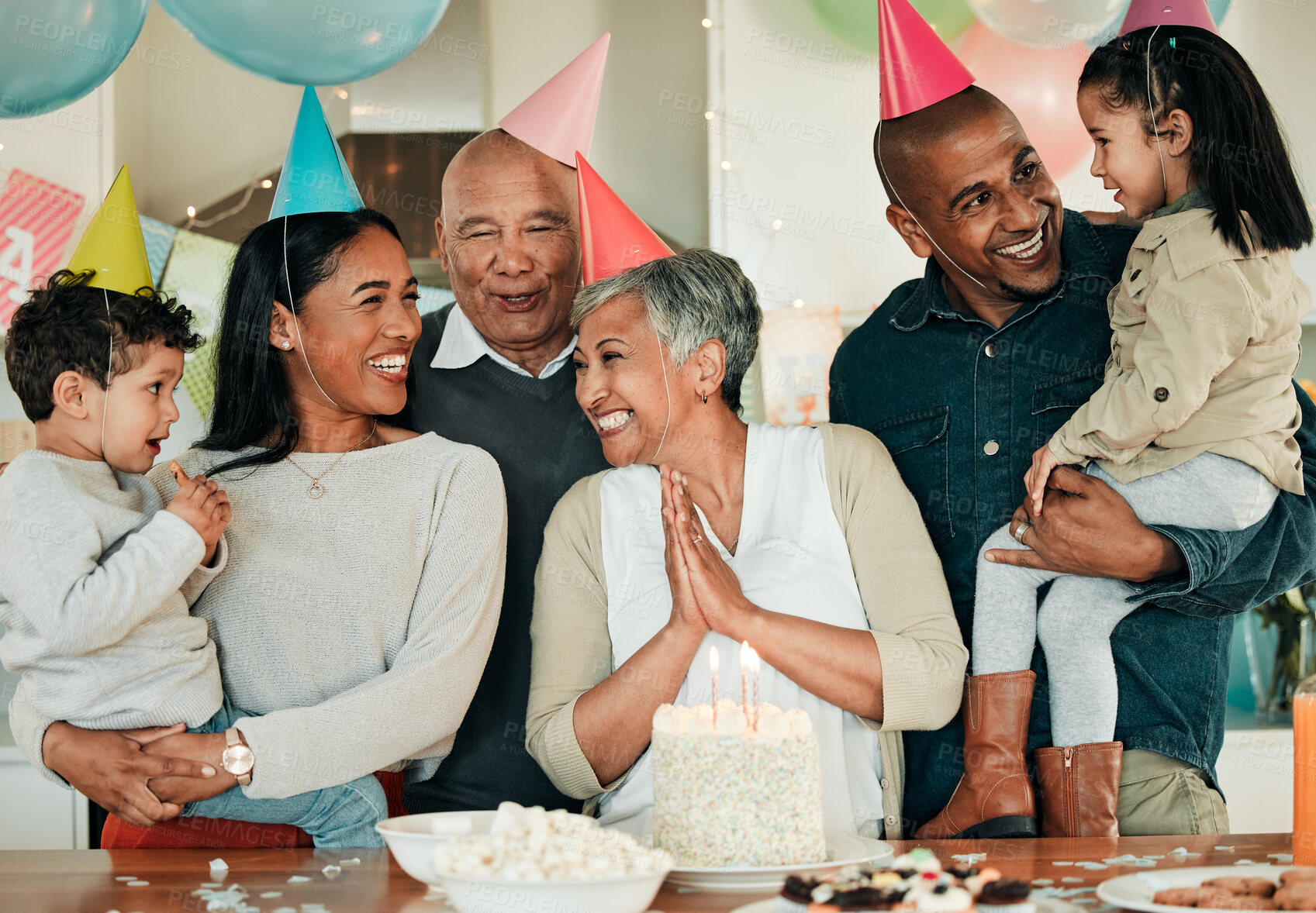 Buy stock photo Happy birthday, grandma or family in home for celebration, bond or growth together. Smile, hat or excited grandparents with cake, love or children siblings in a fun house party or special event