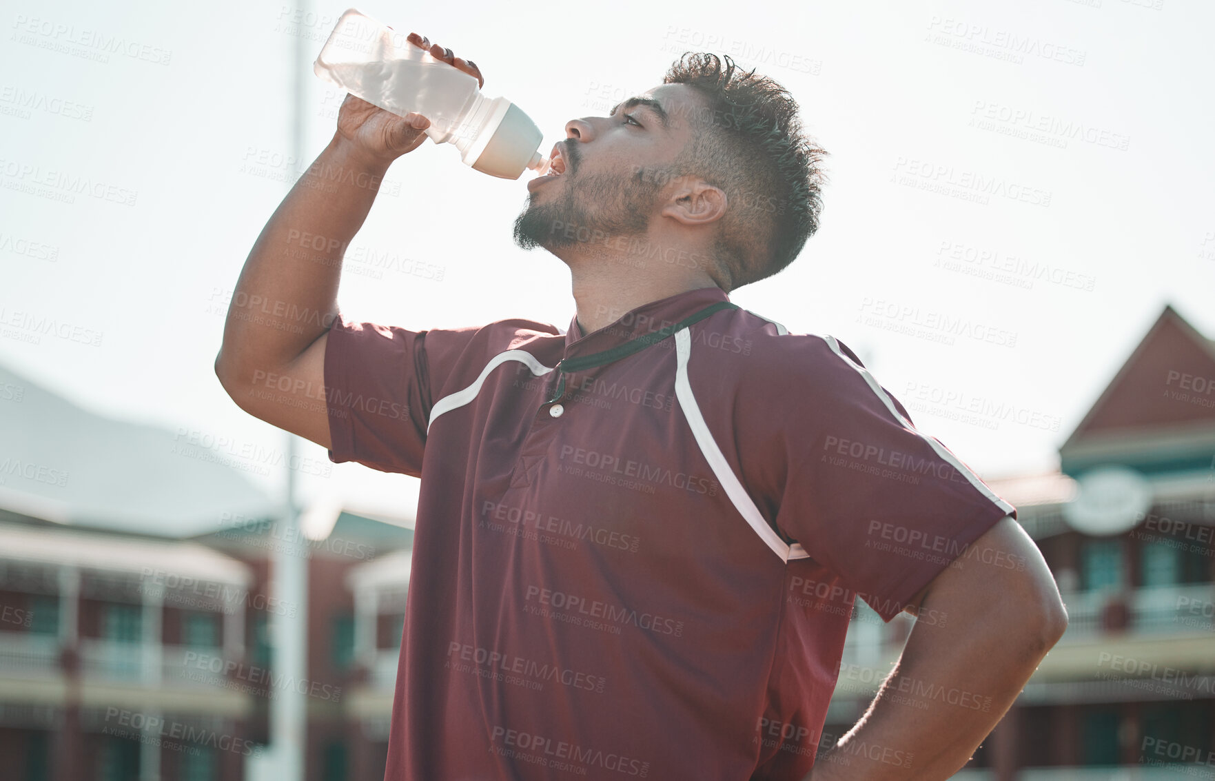 Buy stock photo Football player, drink water and rest on sports field for training completion, workout and exercise outdoors. Fitness, workout and male athlete with liquid bottle for wellness, hydration or practice
