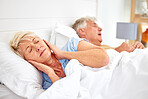 Snoring, problem and woman with frustrated with noise, sound or husband sleeping in bed with wife. Elderly, couple and man snore in sleep in retirement home bedroom and lady with hands on ears