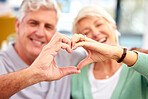 Happy couple, senior or heart hands in home for love, support or bonding in retirement together. Romance blur, hand gesture or romantic old man with a mature woman for care, commitment or trust 