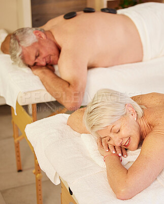Hot stone, back massage and senior couple at spa for luxury, self care and muscle healing treatment. Health, relax and elderly man and woman on a retirement retreat for body therapy at natural salon.