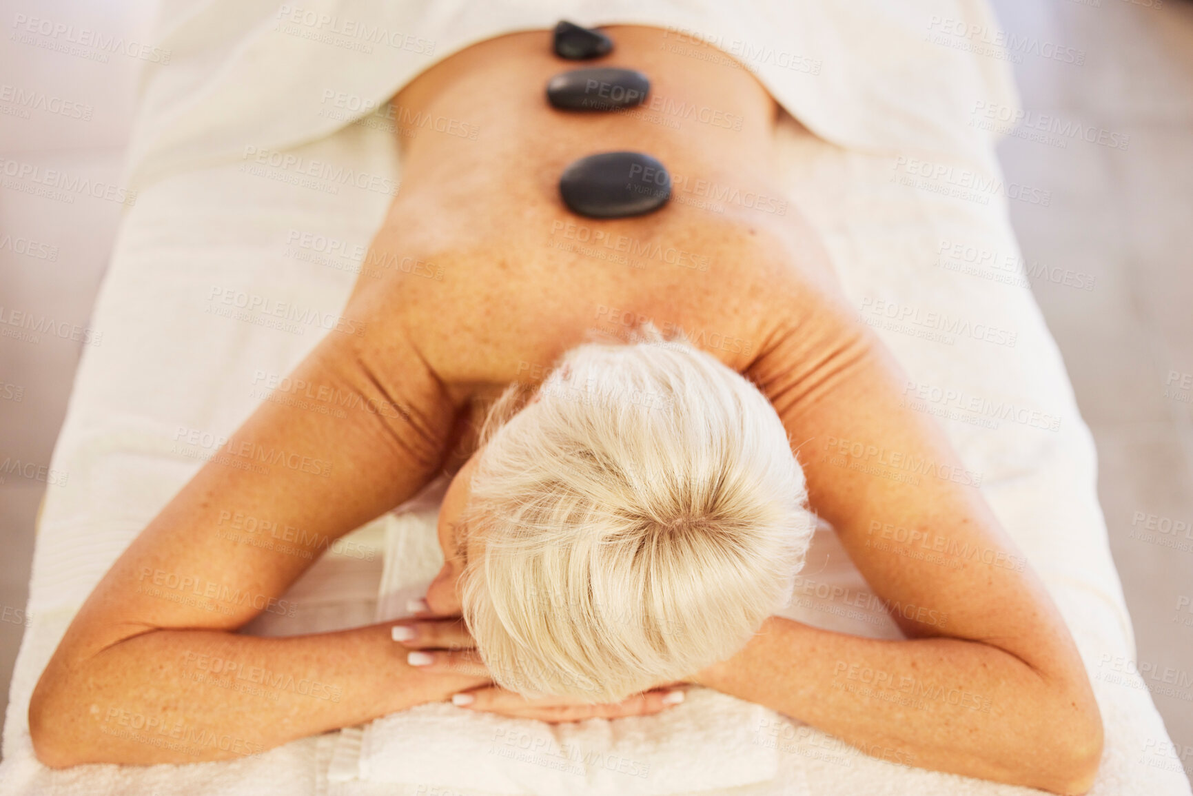 Buy stock photo Senior woman, spa and wellness with stone, massage and relax with health, stress relief and luxury. Salon treatment, elderly person and pensioner with care, resting and spine with beauty and rock