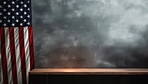 American flag hanging on the side of grey wall with table in front of wall. Background copy space.