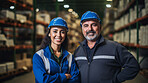 Confident man and woman with hardhats in shipping warehouse smiling at camera