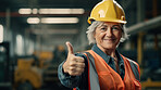 Confident mature older woman with hardhat in shipping warehouse showing thumbsup at camera