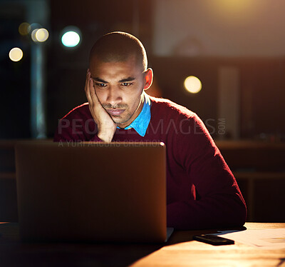 Buy stock photo Sho of a young man looking bored while working late in his office