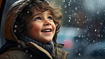 Toddler child cheerfully looking up at falling snow in winter or christmas season