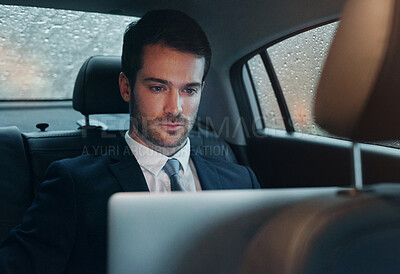 Buy stock photo Shot of a businessman sitting in the backseat of a car working on a laptop