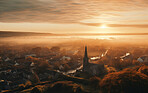 Sunrising on small European town on hillside, covered in mist. Golden hour concept