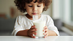 Toddler holding a glass of milk. close-up of baby with a glass of milk