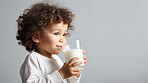 Toddler holding and drinking a glass of milk. close-up of baby with a glass of milk