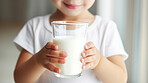 Toddler holding a glass of milk. close-up of baby with a glass of milk