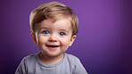 Portrait of a toddler posing against a purple background. happy smiling boy