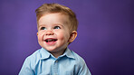 Portrait of a toddler posing against a purple background. happy smiling boy