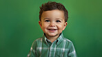 Portrait of a toddler posing against a green background. happy smiling boy