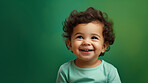 Portrait of a toddler posing against a green background. happy smiling girl