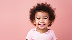 Portrait of a toddler posing against a pink background. happy smiling girl