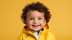 Portrait of a toddler posing against a yellow background. happy smiling boy